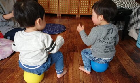 小さいバランスボールの上に座る幼児2人
